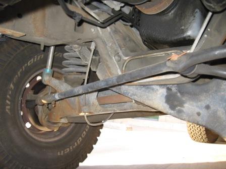1984 Ford Bronco - Close-up of vehicle undercarriage, focusing on suspension and tire details.