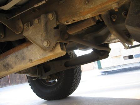 1984 Ford Bronco - The underside of a vehicle shows significant rust on its frame and suspension parts.