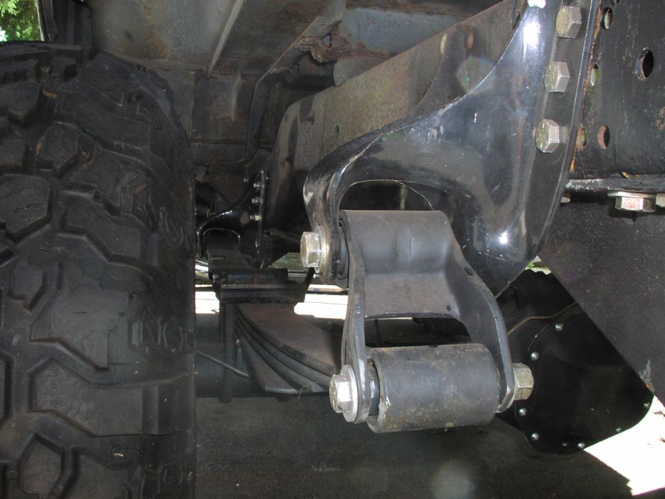 Close-up of a vehicle's rear leaf spring suspension system and tire