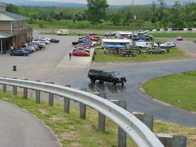 2002 BMW M3 - A black pickup truck navigates a wet turn at a race track event, with spectators and parked vehicles visible in the background.