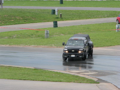 2002 BMW M3 - A black pickup truck is seen on a wet track, possibly during a race or event.