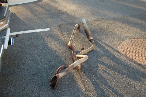 1994 Ford Bronco - A detached exhaust system rests on the ground, showing signs of significant rust and wear.