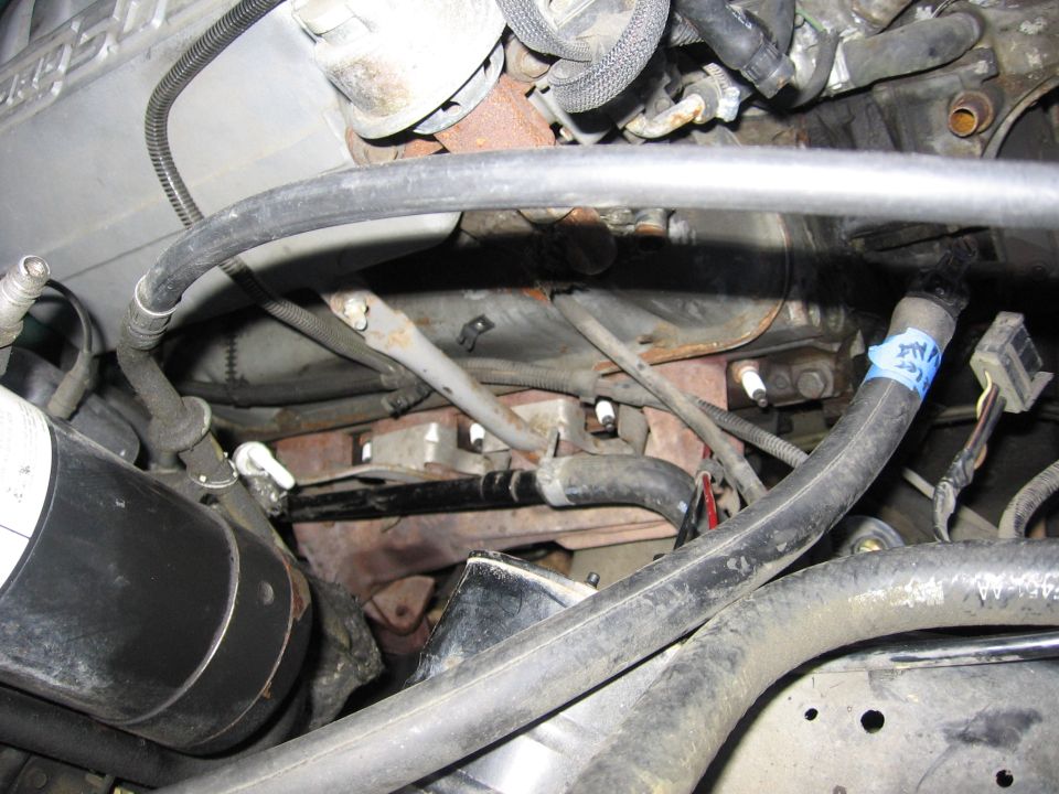 Engine bay with hoses, spark plugs, and wiring visible