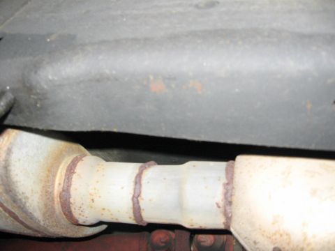 1990 Ford Bronco - Close-up of rusted exhaust system components, likely from a vehicle.