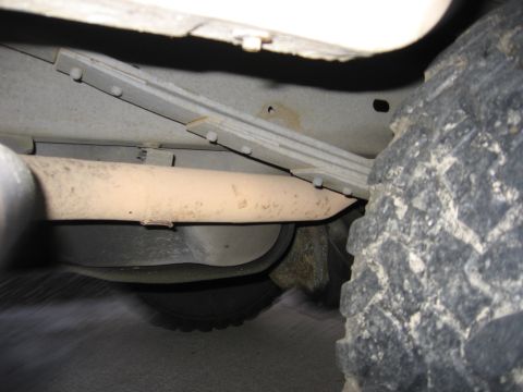 1990 Ford Bronco - Underside view of a vehicle's exhaust pipe and leaf spring suspension system.