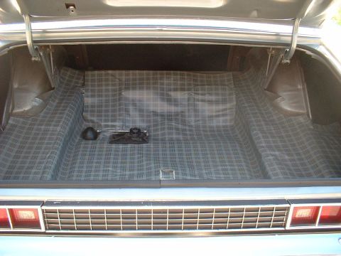 1971 Ford Torino - The trunk of a car is shown with its liner and spare tire tools. The rear bumper and taillights are visible.