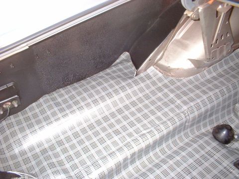 1971 Ford Torino - The interior of a car trunk shows a plaid fabric lining and a metal latch mechanism.