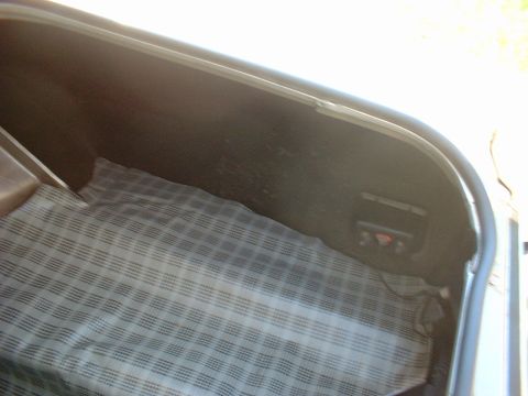 1971 Ford Torino - The interior of a car trunk is shown, a plaid mat and a small control panel on the right side.