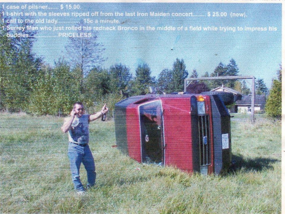 Overturned red and black SUV on its side in a grassy field, man with beer and phone stands nearby