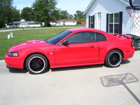 2004 Ford Mustang - A red Ford Mustang is parked in a driveway next to a house with a basketball hoop.
