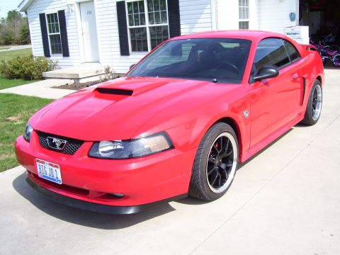 2004 Ford Mustang - A red 2004 Ford Mustang coupe is parked in front of a house.