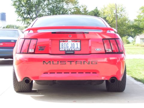 2004 Ford Mustang - The rear of a red 2004 Ford Mustang is shown, its distinctive taillights and a custom license plate.