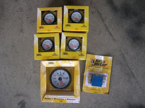 1996 Ford Bronco - A collection of Auto Meter gauges and a fuse set are displayed, ready for installation.