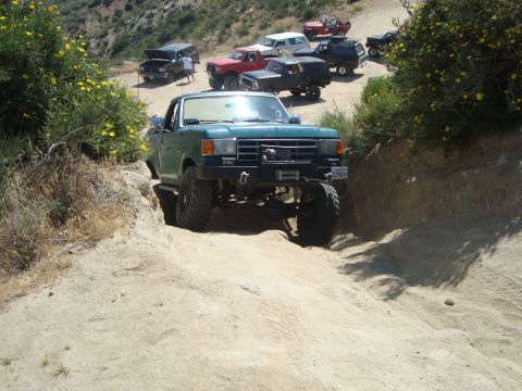 1986 Ford Bronco - A group of modified trucks, including a 1987 Ford F-150, tackle a challenging off-road trail.