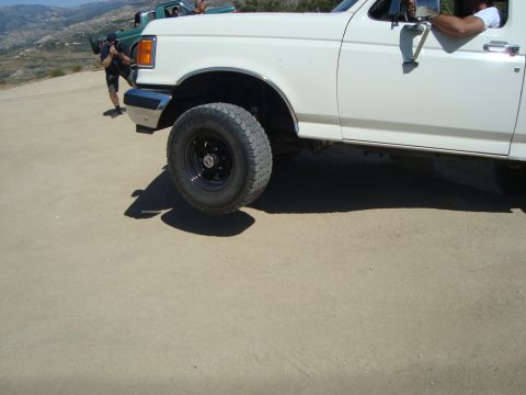 1986 Ford Bronco - White pickup truck with a person in the driver's seat, another vehicle in the background.