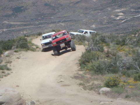 1986 Ford Bronco - Three SUVs navigate a steep, dusty trail in a mountainous, arid landscape.
