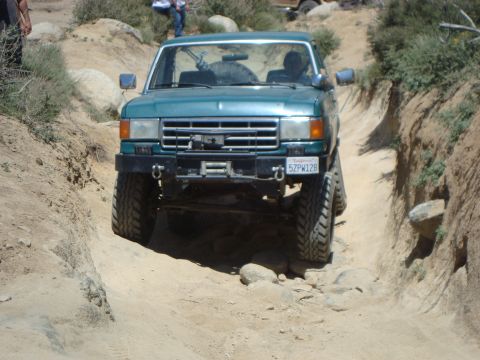 1986 Ford Bronco - Off-road SUV navigating a challenging rocky path.