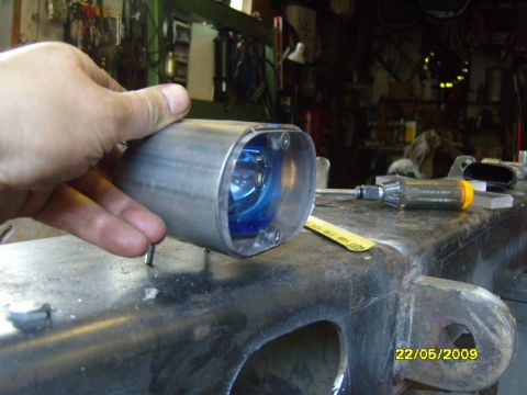 1989 Ford Bronco - A custom exhaust tip with a blue bulb is held by a hand over a workbench in a garage.