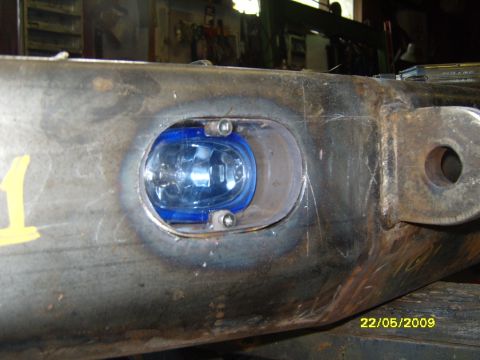 1989 Ford Bronco - A blue fog light is mounted into a heavy-duty metal component, likely part of a vehicle's chassis or bumper system.
