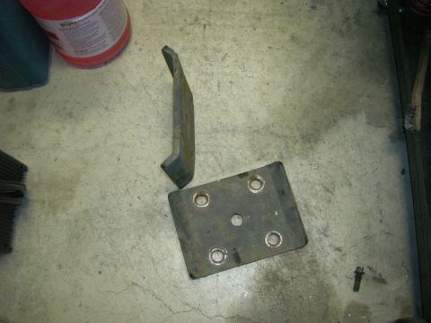 1996 Ford Bronco - Two metal automotive parts are shown on a concrete floor next to a red container.