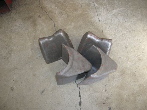 1996 Ford Bronco - Four cast metal brackets are shown on a cracked concrete surface.