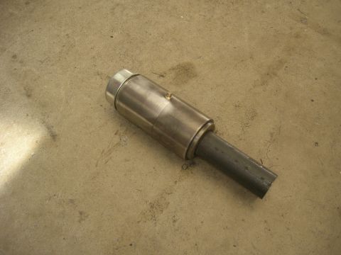1996 Ford Bronco - A close-up view of a metal exhaust component resting on a textured concrete surface.
