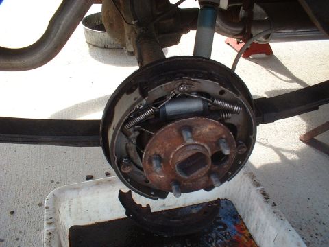 1971 Ford Torino - Rear drum brake assembly removed for service, with old brake fluid collected in a pan.