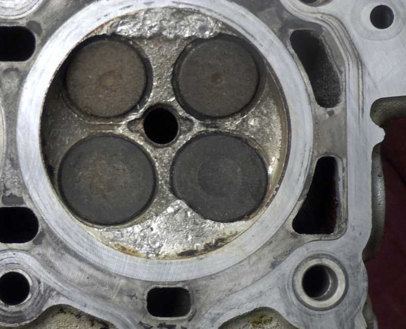 Engine cylinder head with four valves and carbon buildup