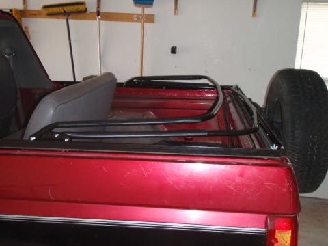 1994 Ford Bronco - The interior of a red SUV is shown, a seat and a spare tire mounted externally.
