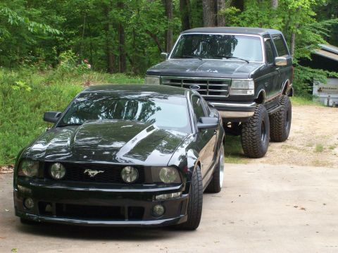 2007 Ford Mustang - A black 2007 Ford Mustang and a lifted Ford Bronco are parked outdoors.