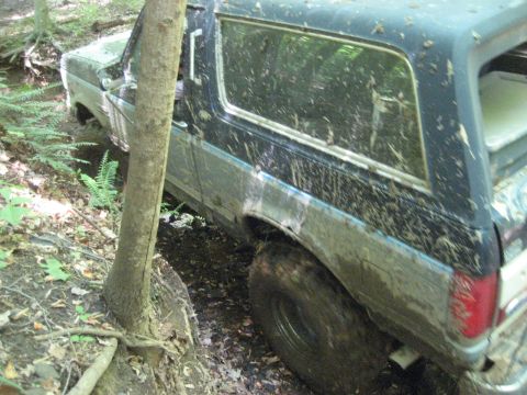 1991 Ford Bronco - This vehicle appears to be stuck in a wooded area, with mud splattered all over its exterior.