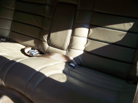 1987 Lincoln Mark VII - Interior view of a car's tan leather seats with seatbelts and a buckle visible.