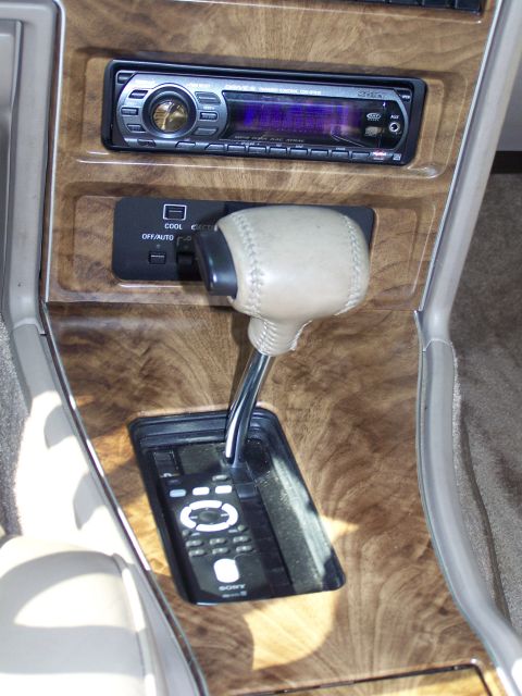 1987 Lincoln Mark VII - The center console features wood grain trim, a car stereo, climate controls, and a gear shifter with a remote control.
