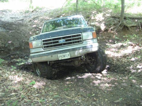 1991 Ford Bronco - Ford Bronco tackling rough terrain on a wooded trail.