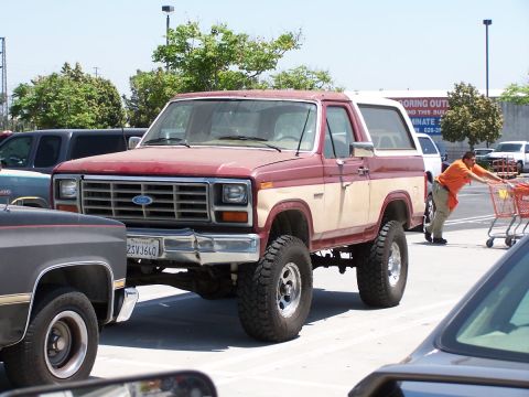 1990 Ford Bronco - This lifted Ford Bronco features a two-tone red and tan paint scheme and aggressive off-road tires.
