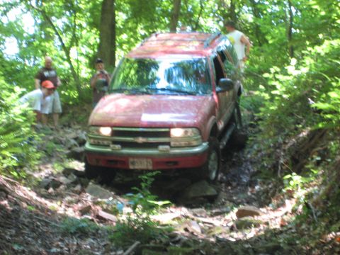1991 Ford Bronco - Chevrolet Blazer tackling an off-road trail with onlookers present.