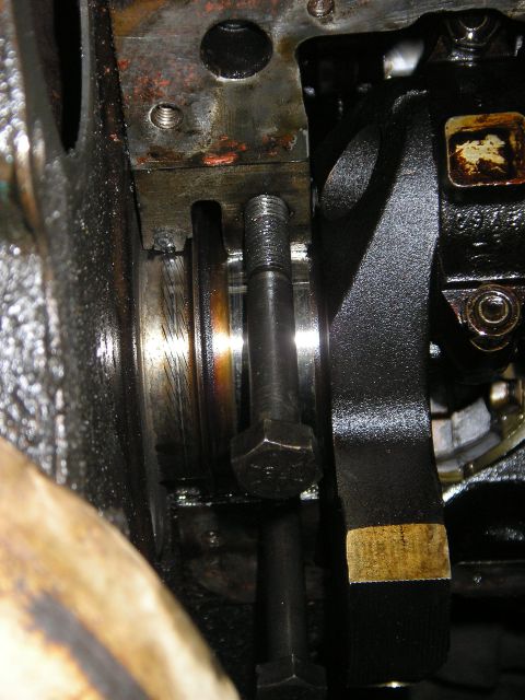 1979 Ford Bronco - Engine crankshaft seal area detail, showing a bolt and a black belt with a yellow stripe.