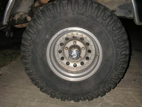 1979 Ford Bronco - Off-road tire and wheel assembly, likely aftermarket. Text 'Texus A/T' is visible on the tire sidewall.