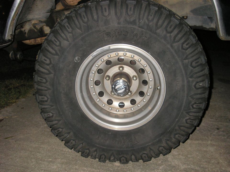 Close-up of an off-road tire with 'Texus A/T' text and a chrome wheel with a 'MM' center cap
