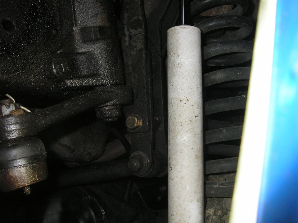 close-up of vehicle suspension parts, including a shock absorber and coil spring