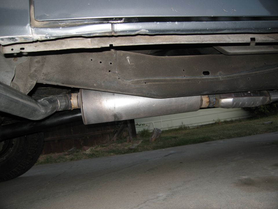 Underside view of a vehicle's exhaust system, showing muffler and catalytic converter