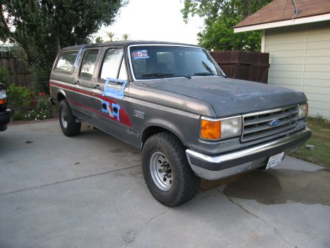 1986 Ford Bronco - This 1986 Ford Bronco SUV is shown in a driveway with a red stripe accent and blue tape on the driver's side door.