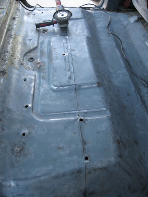 1986 Ford Bronco - A grinder tool sits on the bare metal floor of a vehicle undergoing restoration.