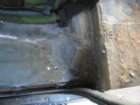 1986 Ford Bronco - The interior floor of a vehicle shows signs of wear and tear, with some debris accumulated.