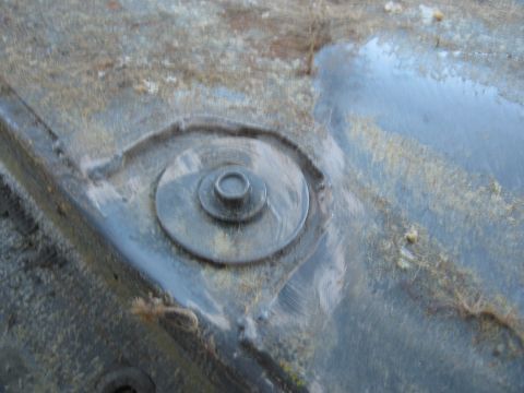 1986 Ford Bronco - Close-up of a bolt on the floor of a vehicle, showing signs of wear and tear.