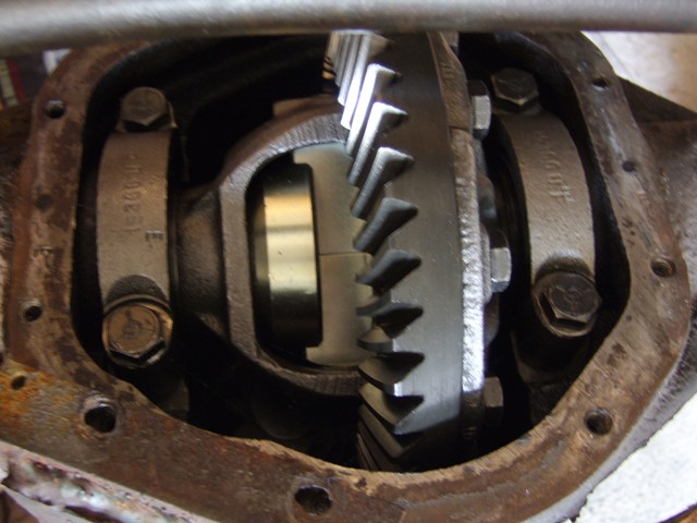 Close-up of differential gears inside a rusty housing. Part numbers are visible on the bearing caps