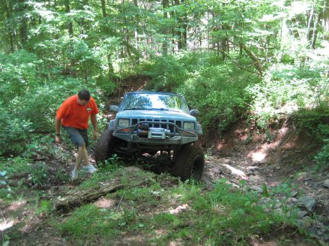 1991 Ford Bronco - A blue Jeep Cherokee navigates a challenging, rocky off-road trail.