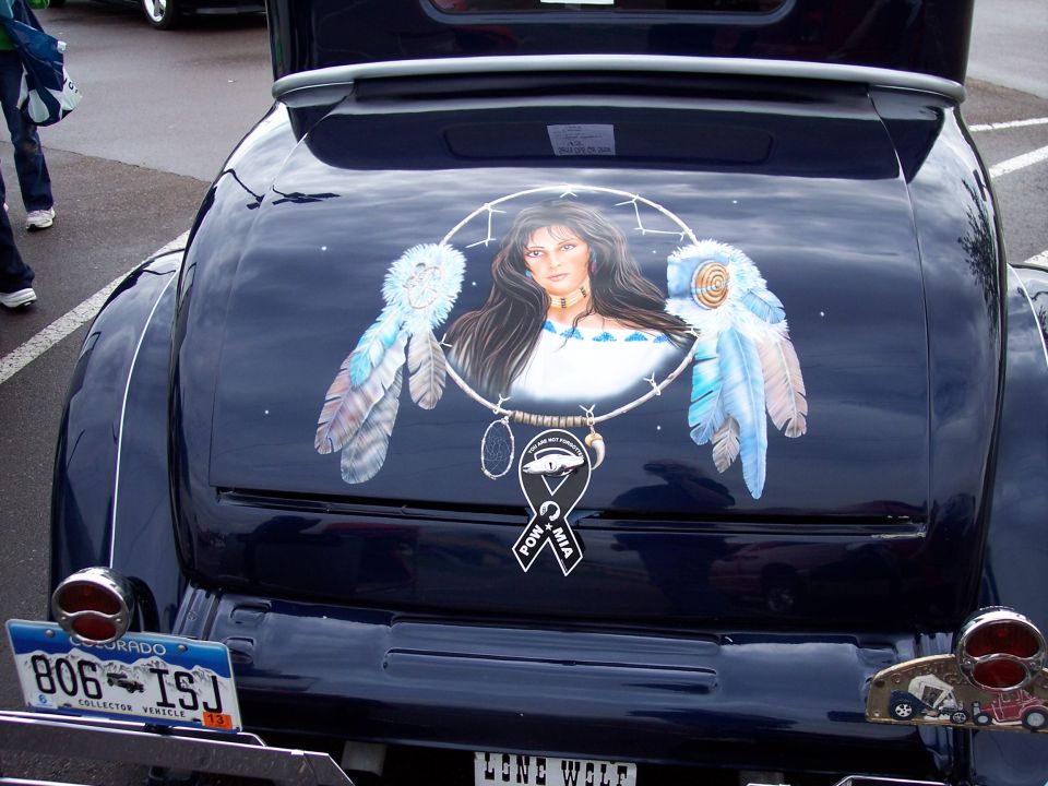 Dark blue car trunk lid with custom painting of a Native American woman in a dreamcatcher, POW MIA ribbon below. Colorado license plate 806 ISJ