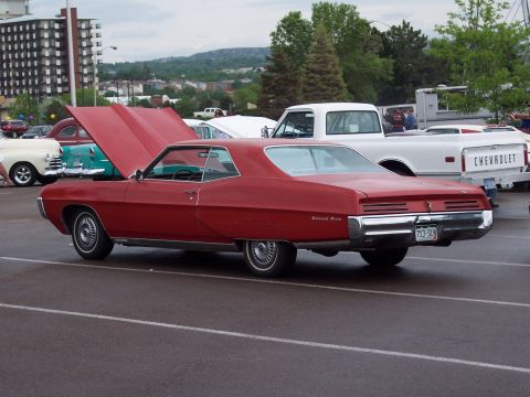 1972 Ford Ranchero - A red 1969 Pontiac Grand Prix coupe is parked with its hood open, alongside other vehicles.
