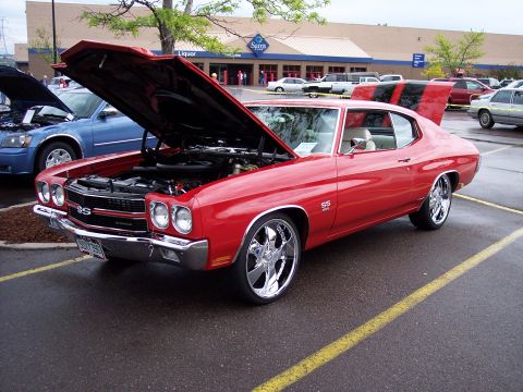1972 Ford Ranchero - A red muscle car, likely a 1970 model, is displayed with its hood and trunk open in a parking lot.